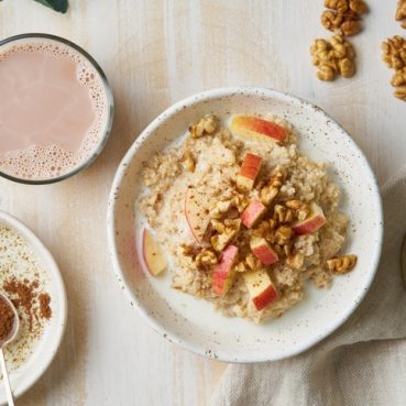 Oatmeal with apple, nuts, honey and cup of chocolate on white wooden light background. Top view. Healthy diet breakfast